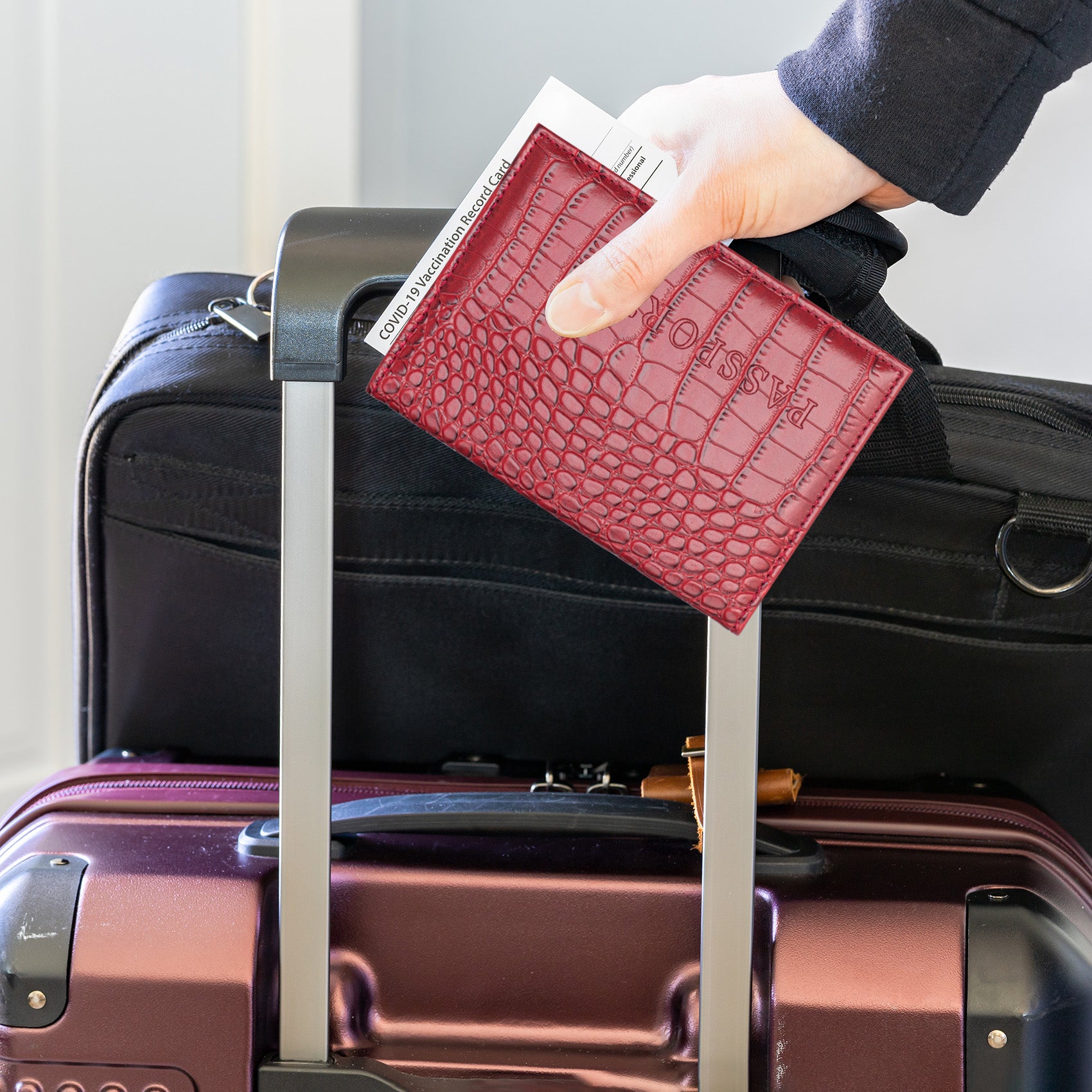 pochette passeport cuir crocodile rouge au dessus d'une valise