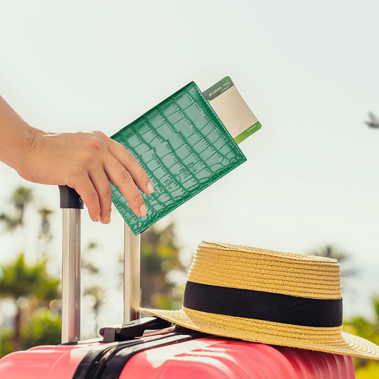 pochette passeport cuir crocodile vert au dessus d'une valise