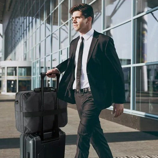 homme qui sort de l'aéorport avec valise et sac de voyage convertible sac à dos