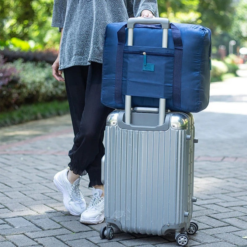 homme avec sac voyage pliable bleu sur sa valise
